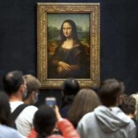 Visitors wearing face masks wait to see the Mona Lisa at the Louvre Museum on Monday. The most visited museum in the world reopened to the public after closing in March.